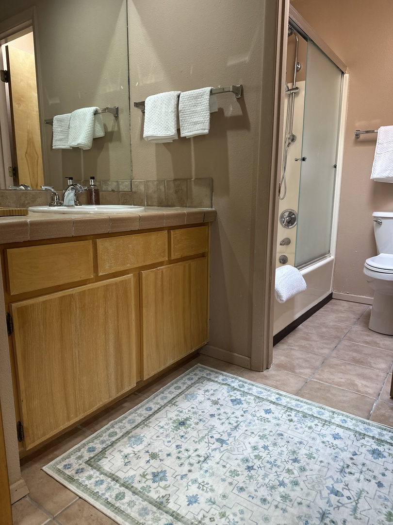 Unwind in your spacious bathroom with dual vanities, a glass-enclosed shower, and plush towels ready for your comfort.