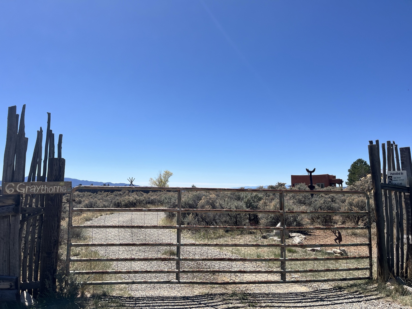 Property entrance gate opens to desert landscapes and mountain views under endless blue skies.