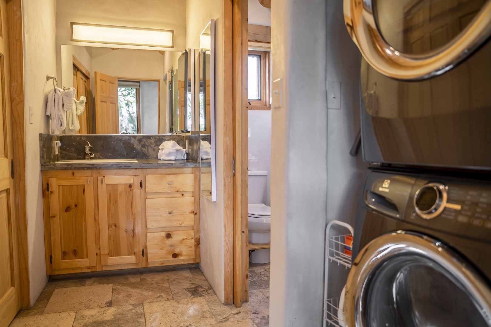 Your own private bathroom retreat features handcrafted knotty pine cabinetry, elegant dark marble countertops, and fresh linens waiting for you. A convenient washer and dryer complete this thoughtfully designed space.