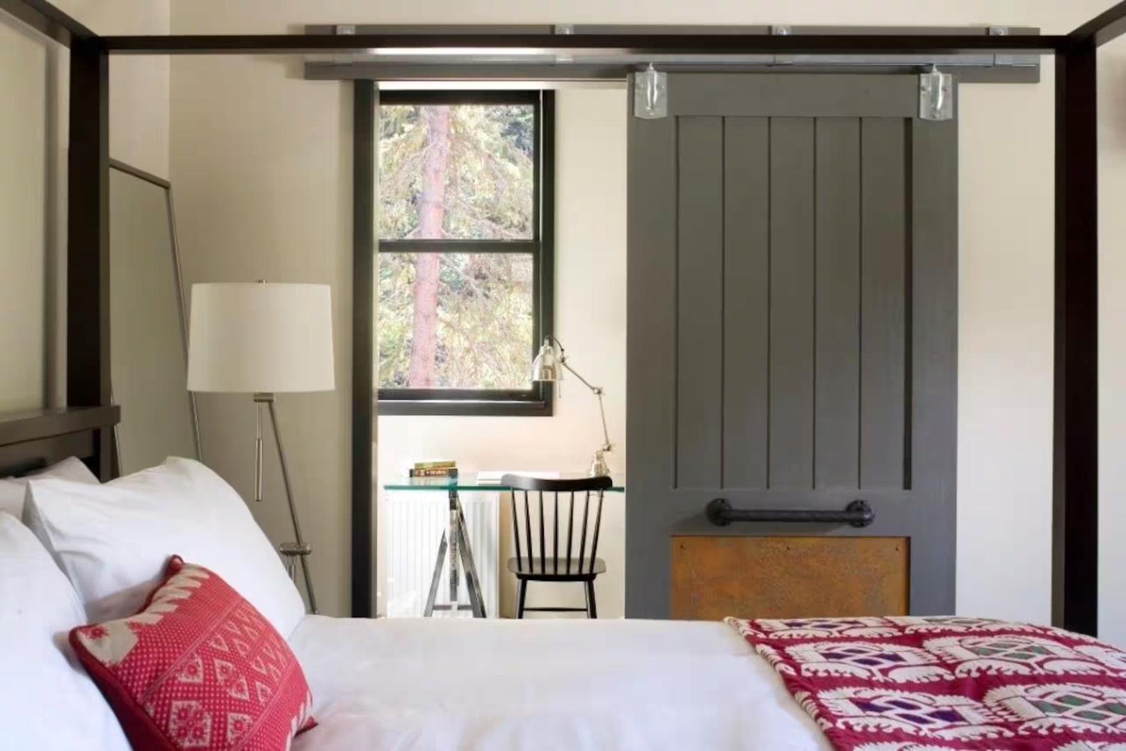 Sink into crisp white linens in your charming bedroom, where rustic elegance meets modern comfort. A sliding barn door leads to your work nook, and natural light frames peaceful forest views.