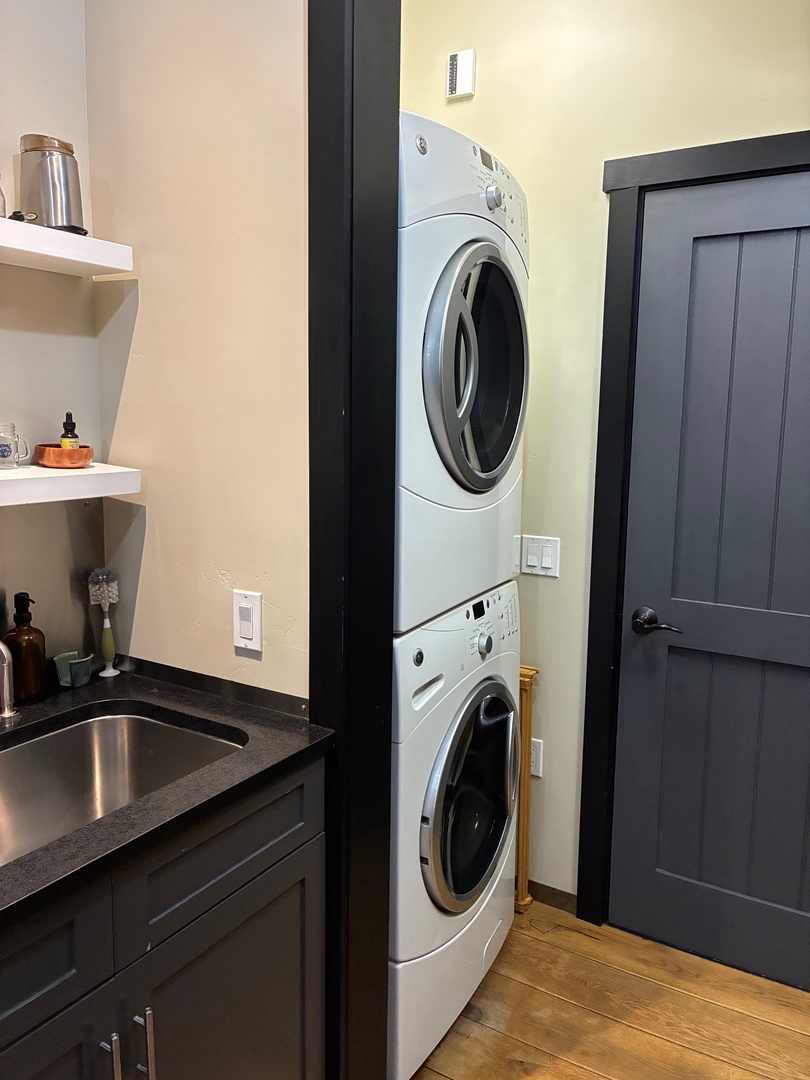 Your own in-unit washer and dryer make laundry effortless during your stay, tucked neatly alongside a convenient sink and shelving for supplies.