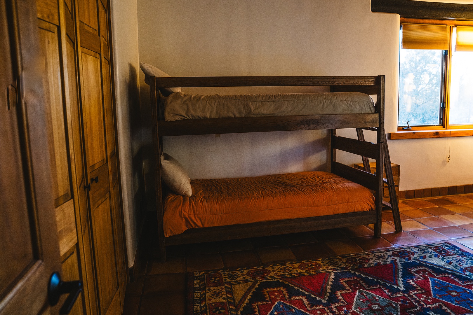 Your rustic bedroom features sturdy wooden bunk beds with colorful linens, perfect for families or friends sharing adventures together.