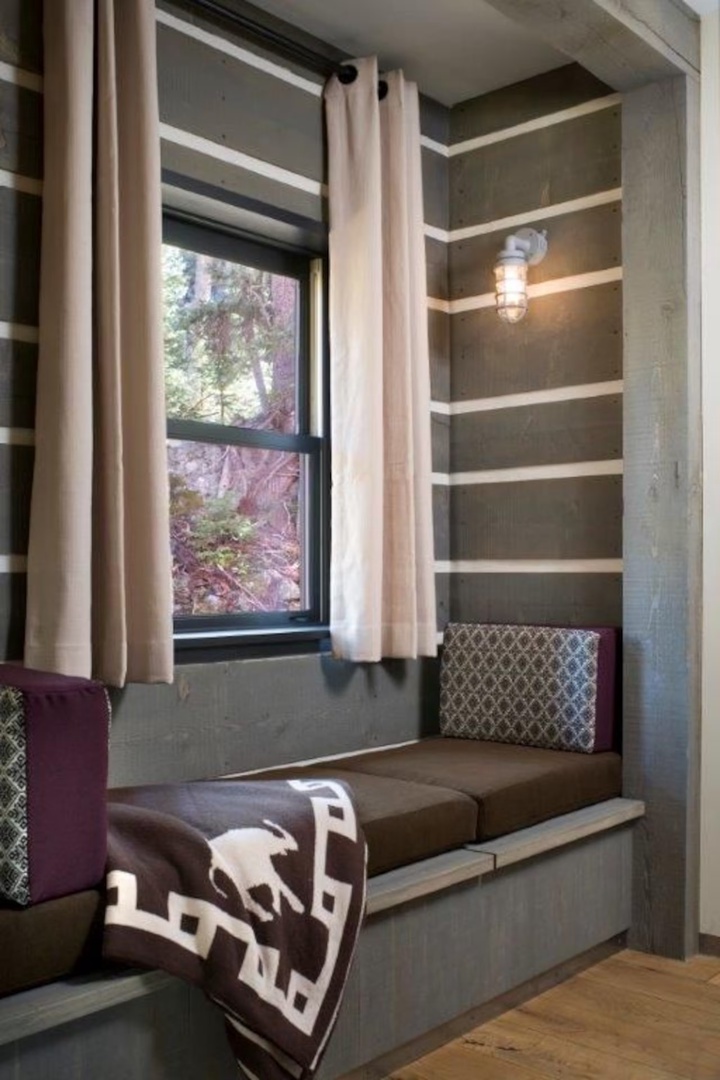 Curl up in your own cozy reading nook with built-in bench seating, soft pillows, and a natural woodland view through the window—perfect for quiet mornings with a book.