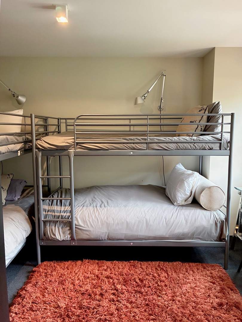 Your group will love this cozy bunk room, where everyone gets their own comfortable sleeping space. The soft rug and thoughtful lighting create a warm retreat after a day of adventure.