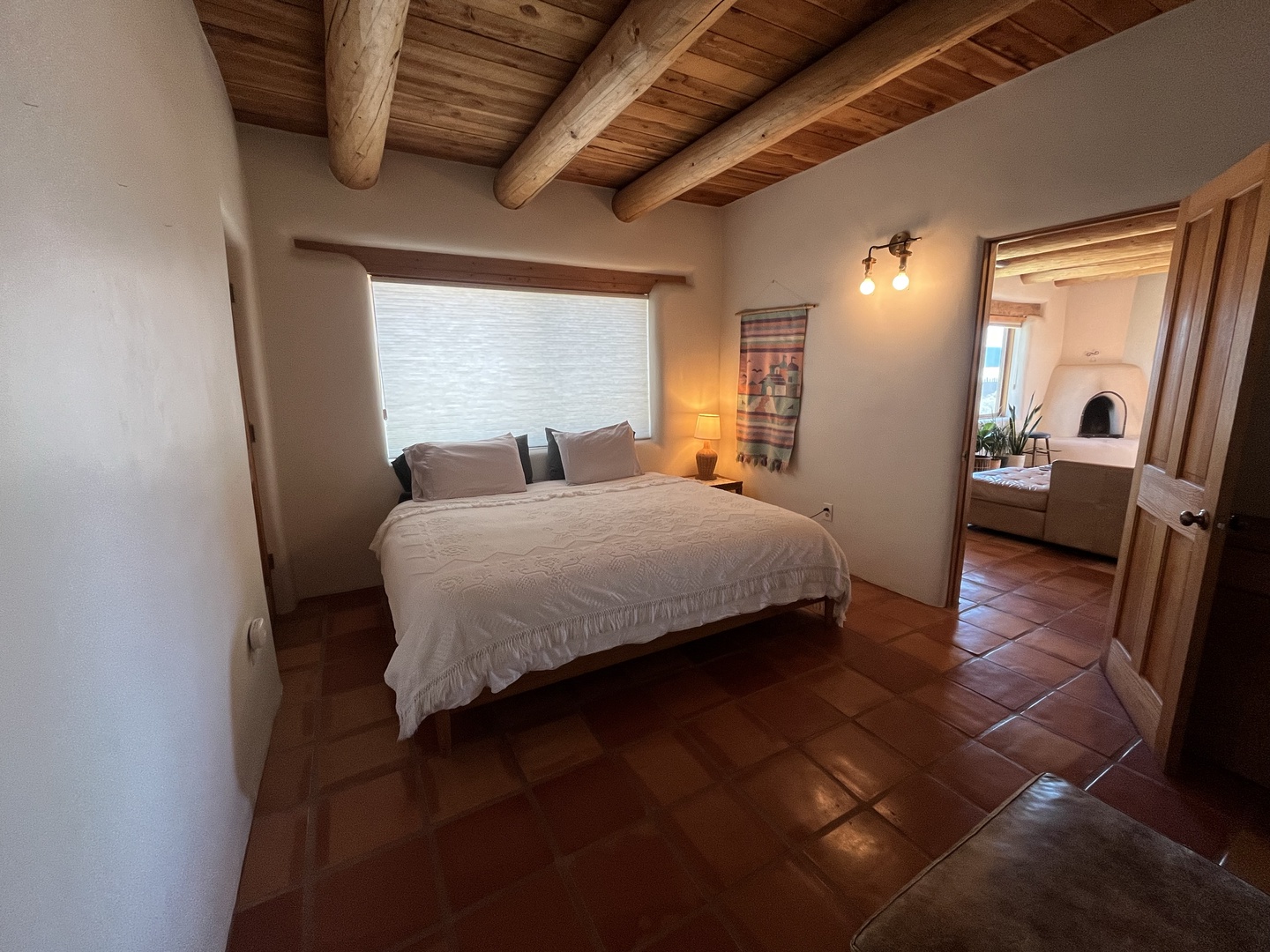 Drift off under rustic wooden beams in this cozy bedroom, where warm terracotta tiles and natural textures create your perfect retreat.