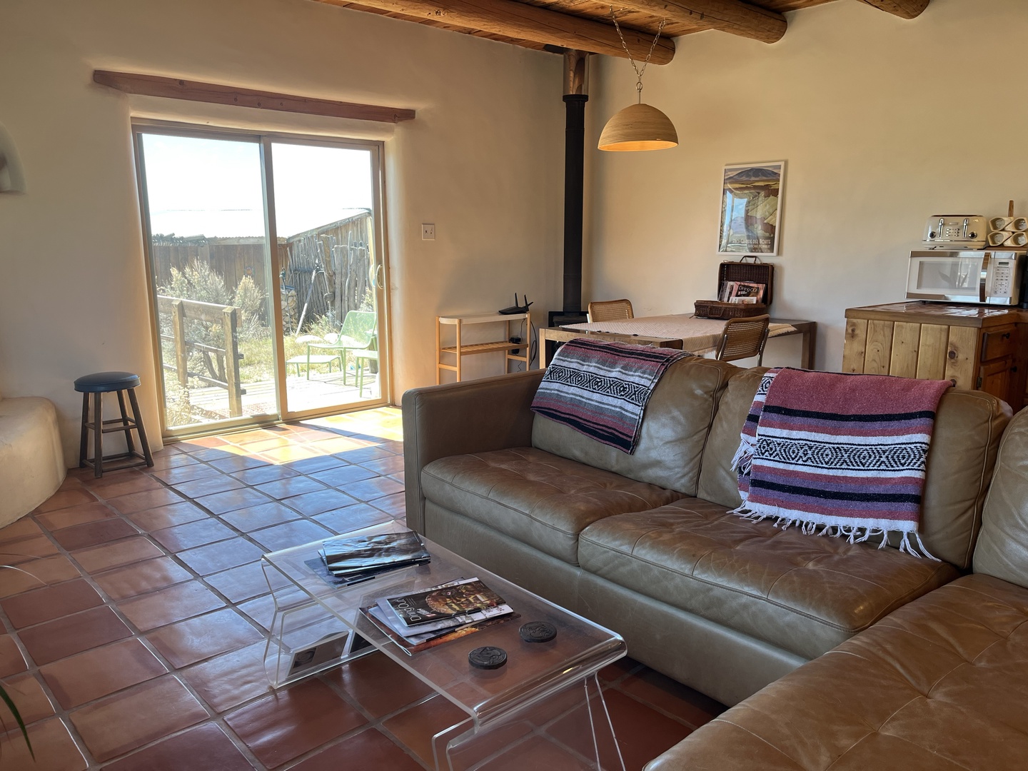 Relax in your rustic living space with exposed beams, cozy leather seating, and garden views through sunny windows.