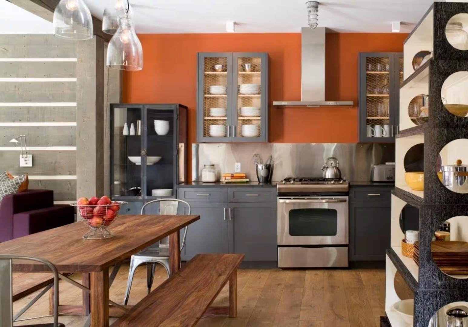 Gather around this warm, modern kitchen where your culinary adventures begin. The bold orange accent wall and sleek gray cabinetry create an inviting space to cook, dine, and make memories together.