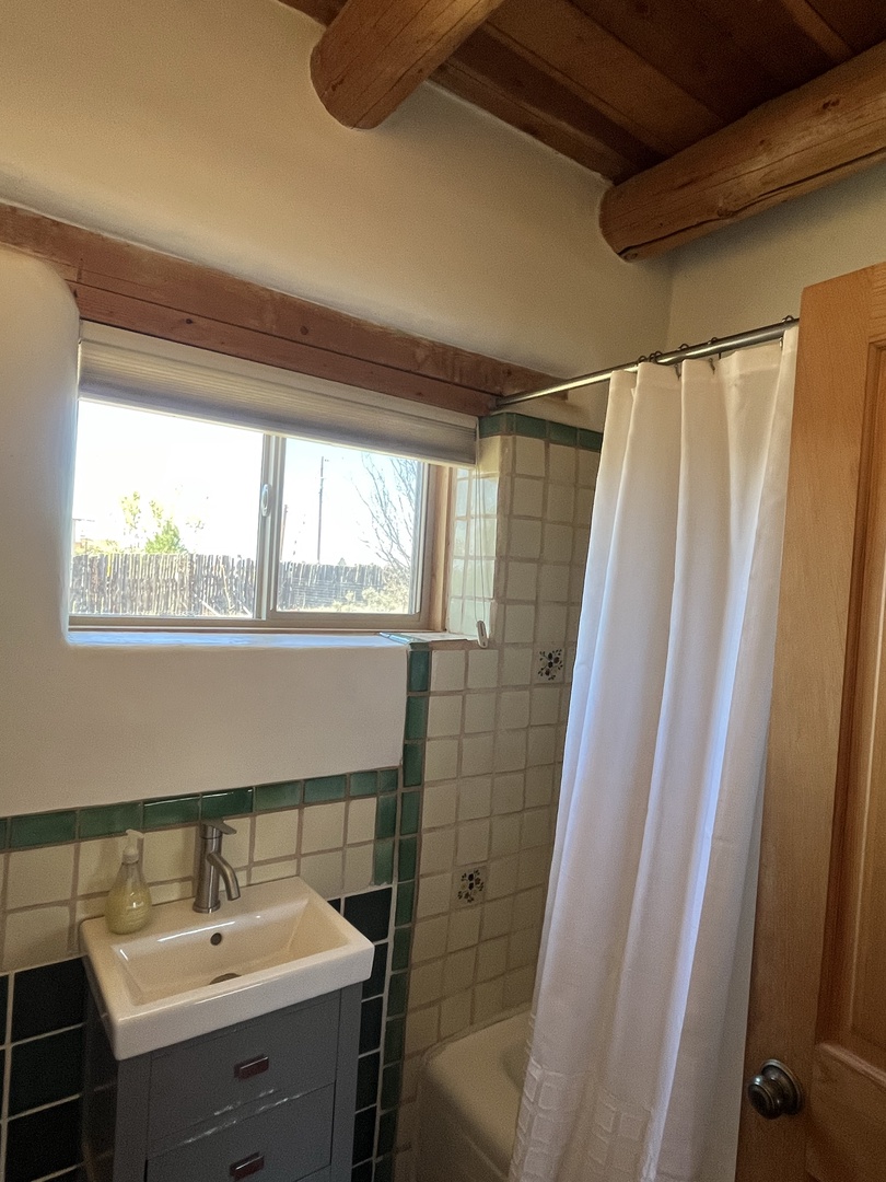 Step into your charming bathroom with rustic ceiling beams and fresh white curtains framing garden views for peaceful morning routines.