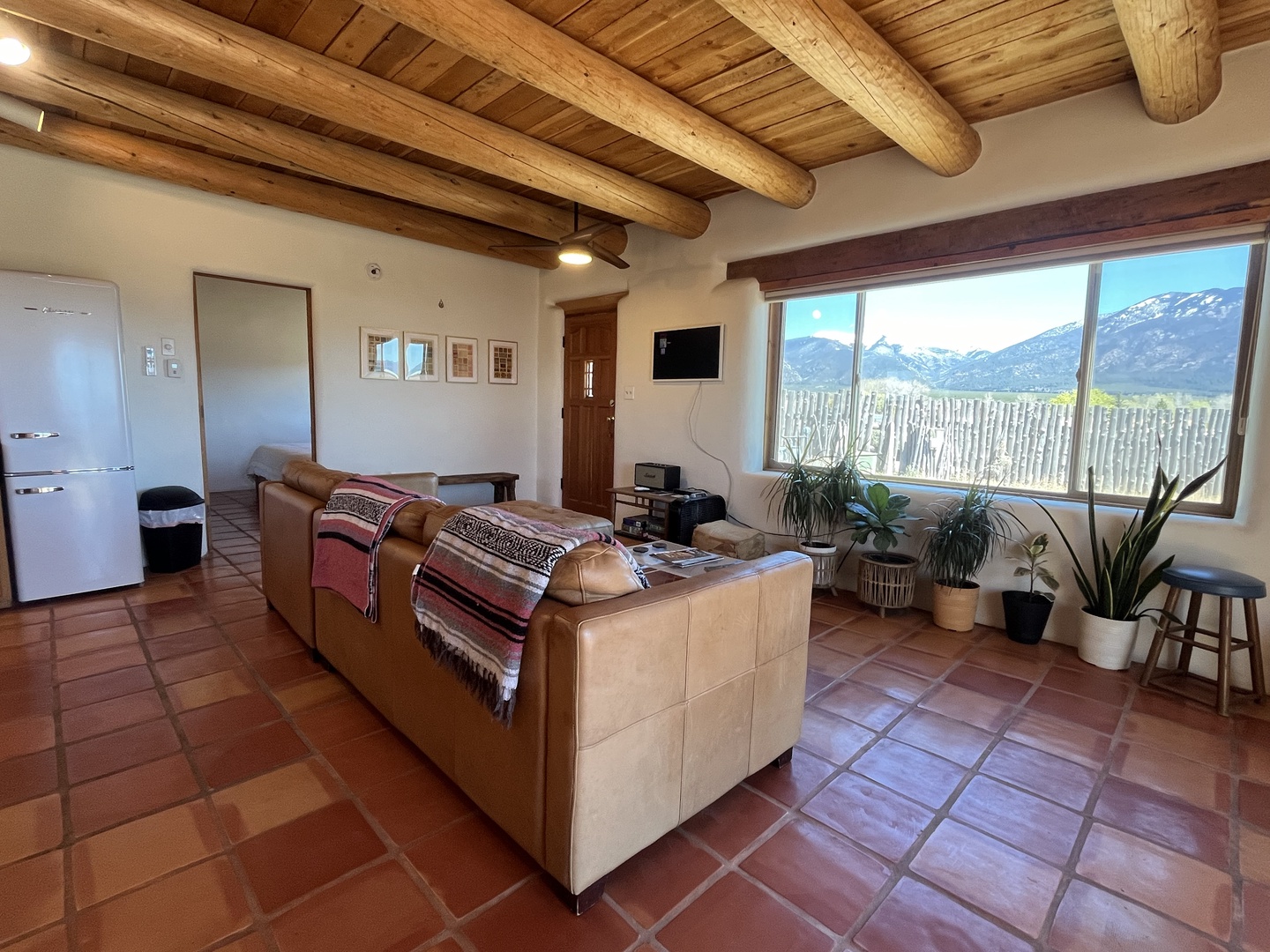 Relax under rustic wooden beams while soaking in breathtaking mountain views through floor-to-ceiling windows in your cozy living space.
