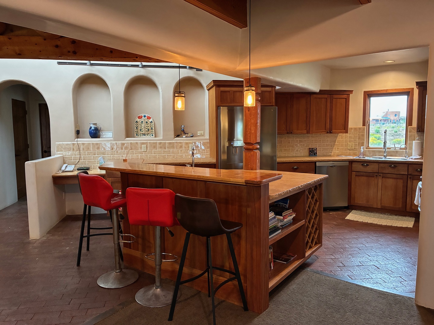 Gather around the custom wood island with seating for casual meals or coffee, surrounded by rich cabinetry, tile accents, and natural light streaming through the windows.