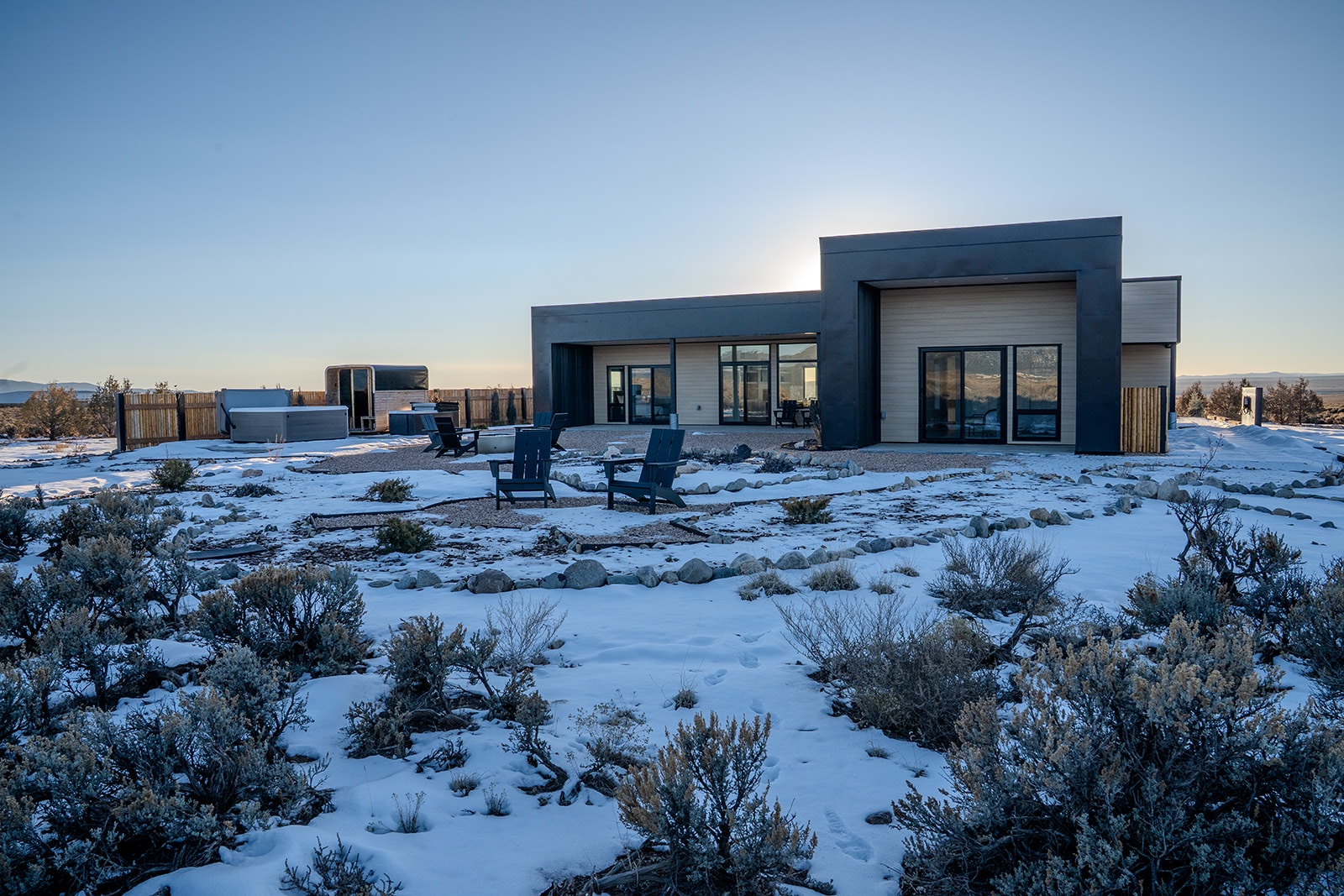 Modern desert retreat surrounded by snow-covered landscape and natural vegetation, offering stunning panoramic mountain views.