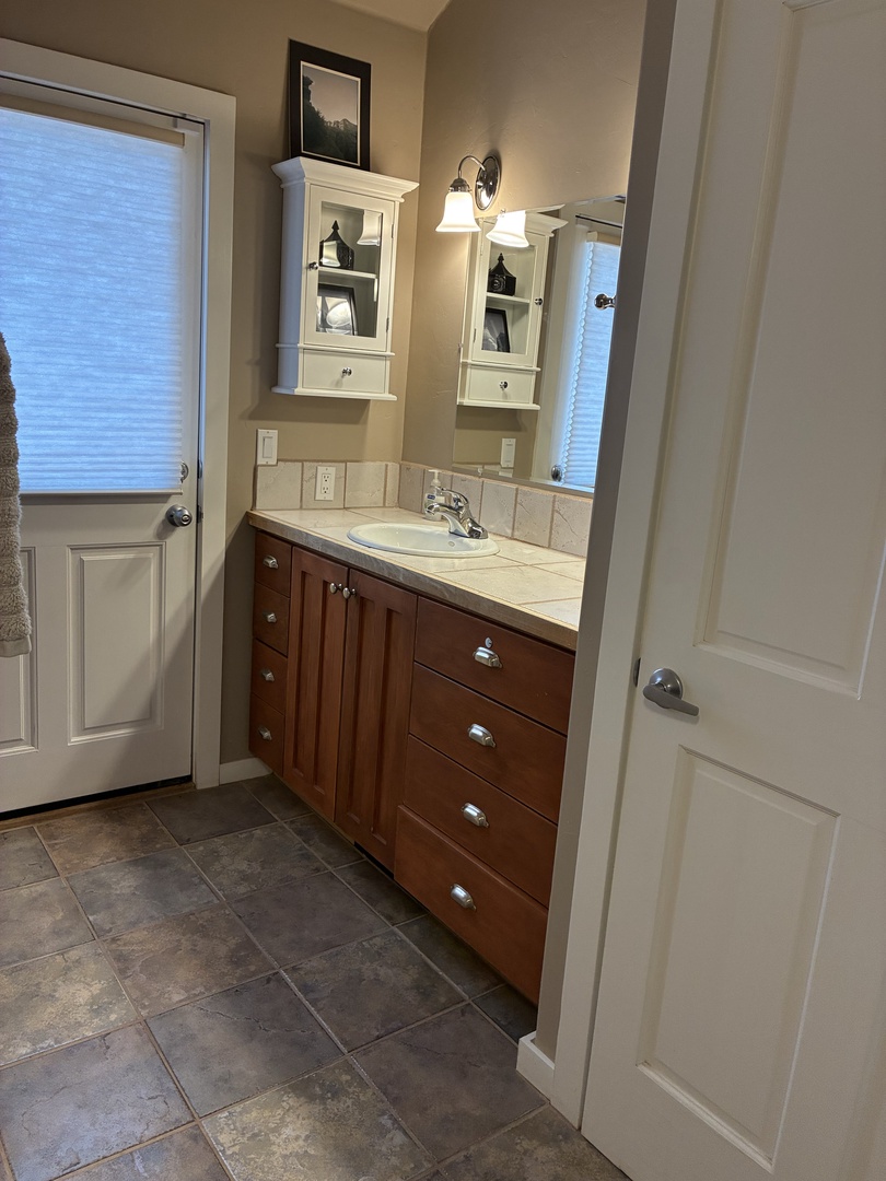 Your bathroom offers a bright, welcoming space with warm wood vanity storage and cheerful natural light streaming through the windows.