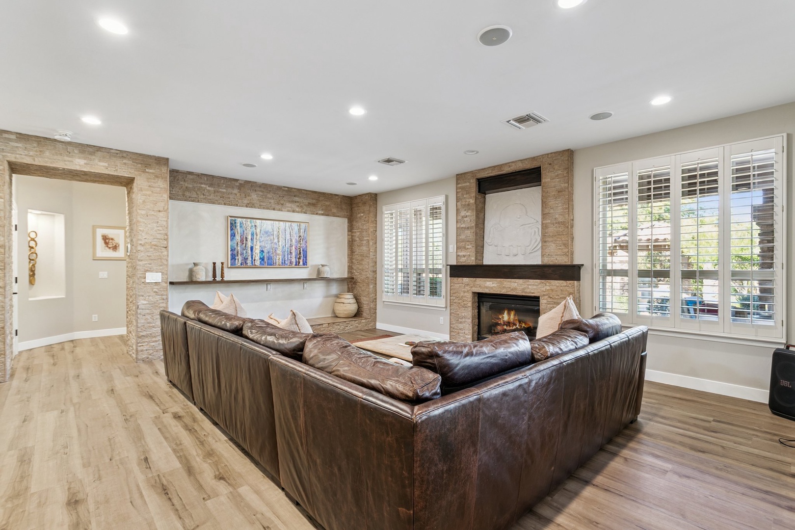 Unwind in your spacious living room, where rich leather seating surrounds a cozy fireplace and natural light streams through elegant shutters.