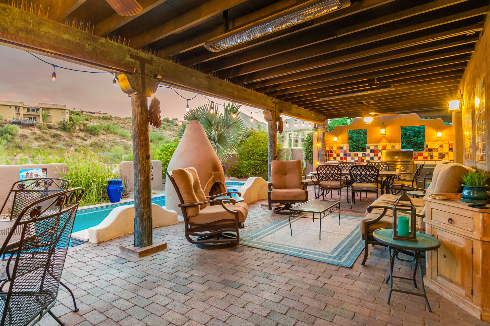 Covered patio with dining table, lounge area with outdoor TV, and outdoor BBQ Kitchen.