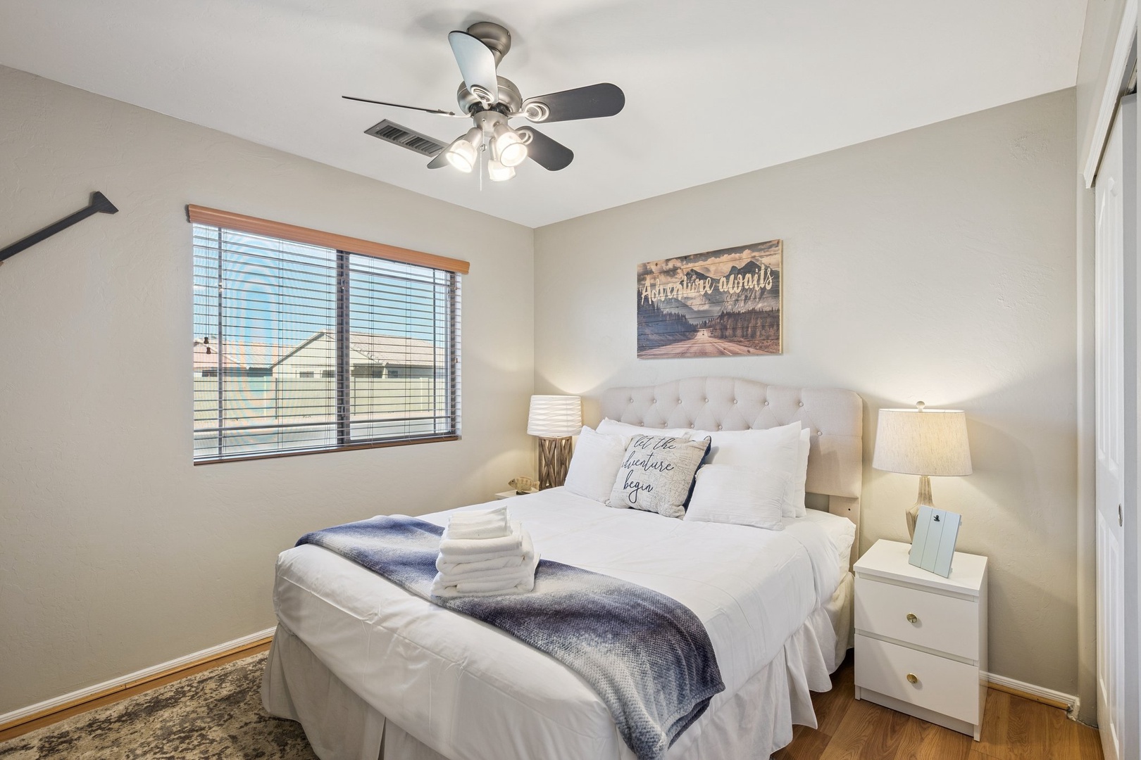 Drift off in this cozy bedroom featuring a plush tufted headboard, soft linens, and a gentle ceiling fan to keep you comfortable.