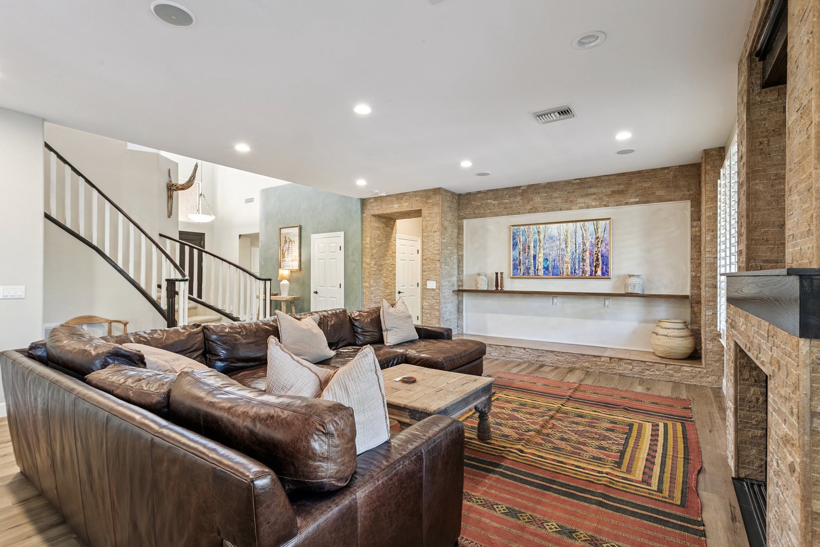 Sink into plush leather sofas by your cozy fireplace, where warm brick accents and soft lighting create the perfect retreat.