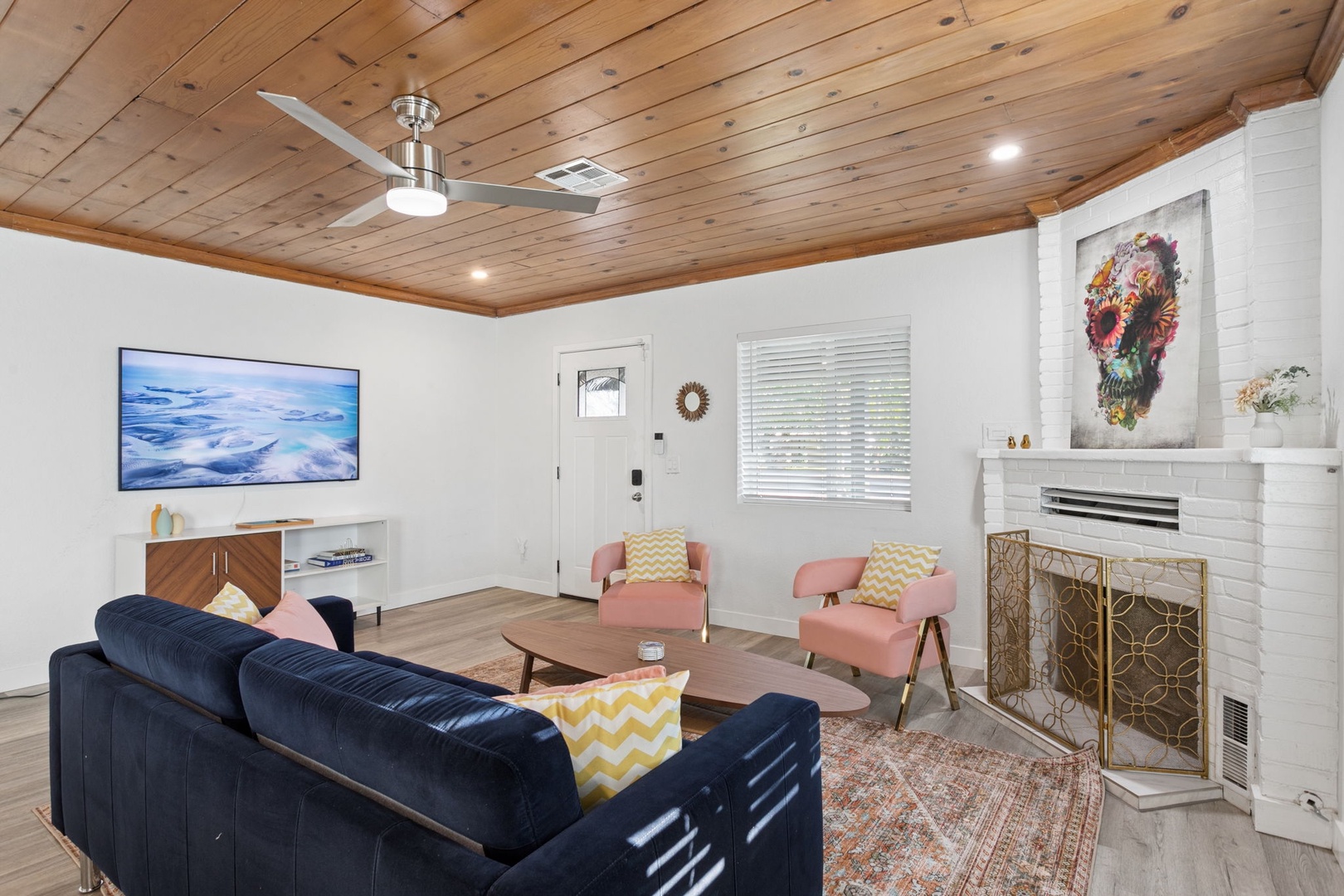 Relax in your stylish living room with plush seating, warm wood ceiling, and crackling fireplace creating the perfect cozy atmosphere.