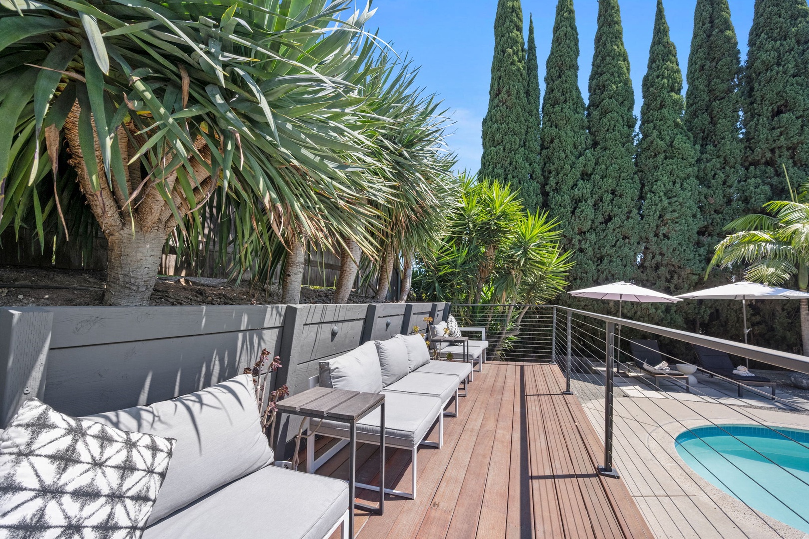 Private deck with plush lounge chairs, tropical landscaping, and pool access creates your perfect sunny retreat surrounded by Mediterranean-inspired greenery.