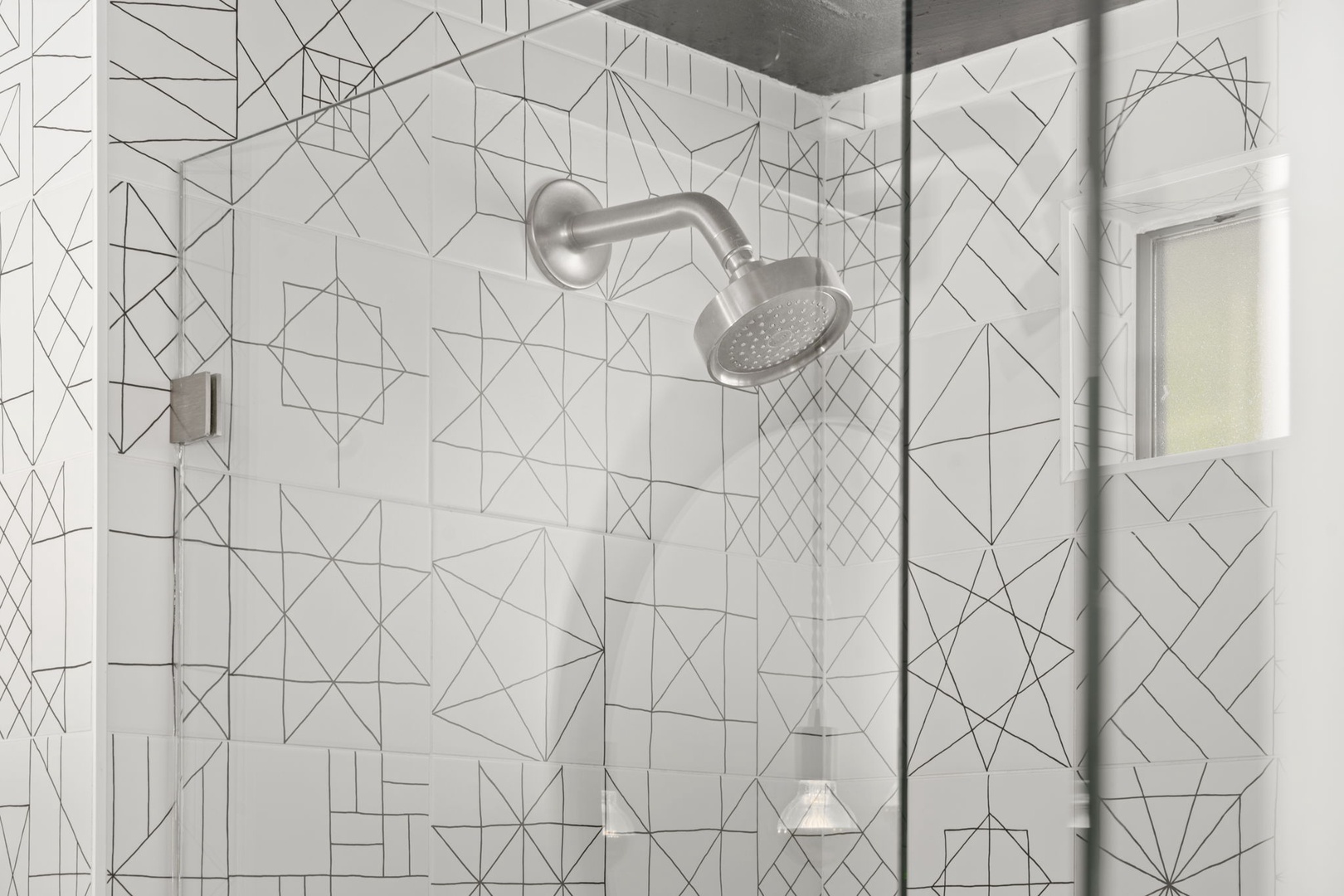 Rinse away stress under your private rain showerhead surrounded by striking geometric tiles that transform daily routines into moments of modern artistry.