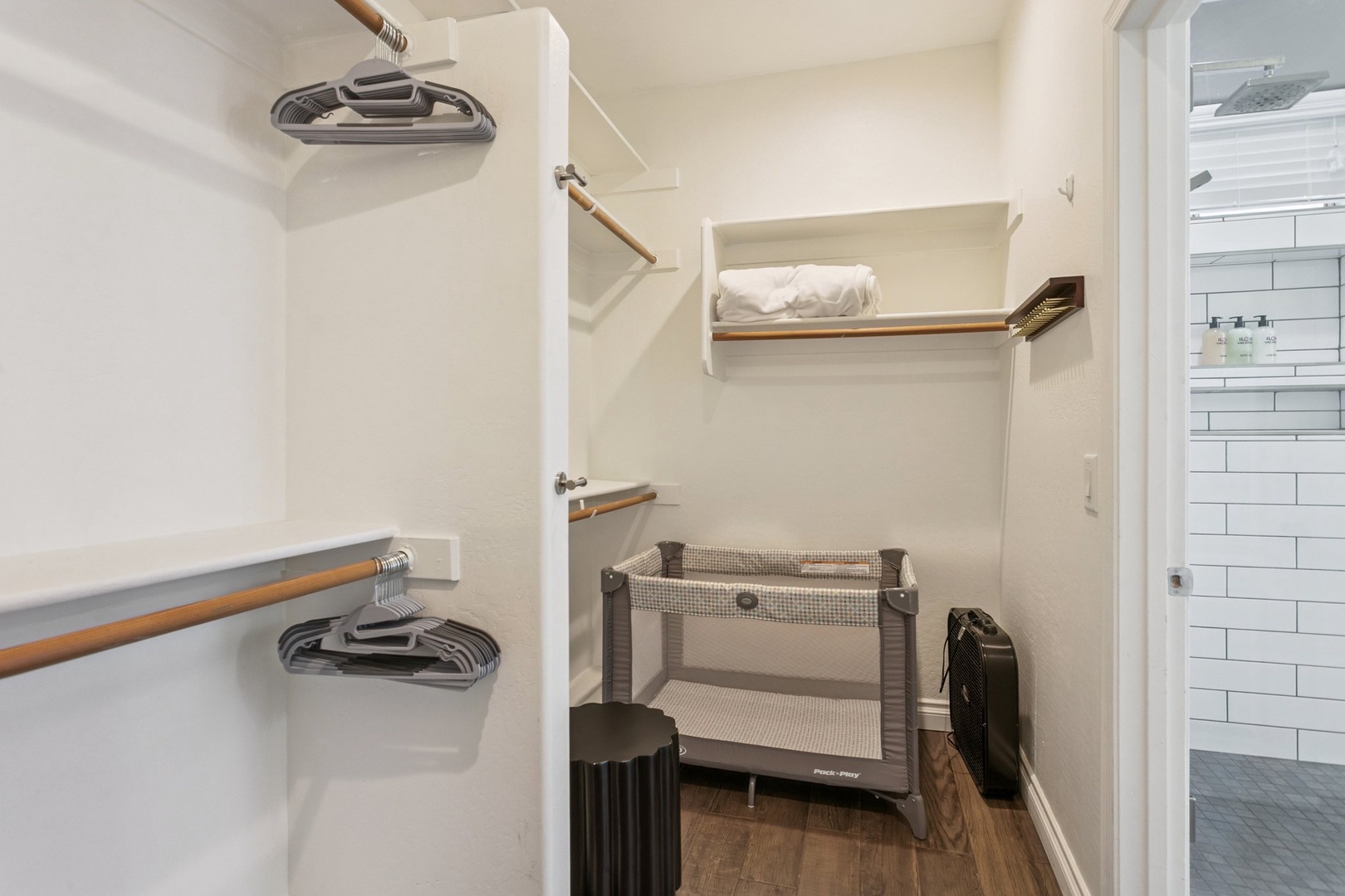 Your spacious walk-in closet offers organized storage with wood-accented rods and shelving, plus room for a travel crib.