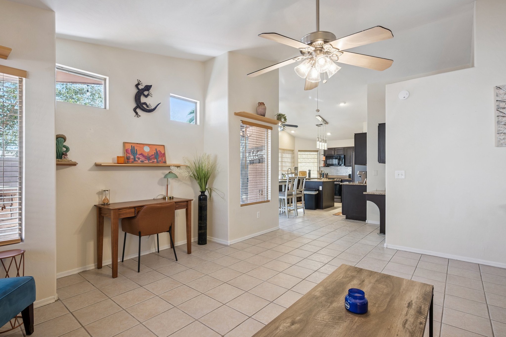 Relax in your bright, open living space with ceiling fan, workspace, and seamless flow to the modern kitchen.