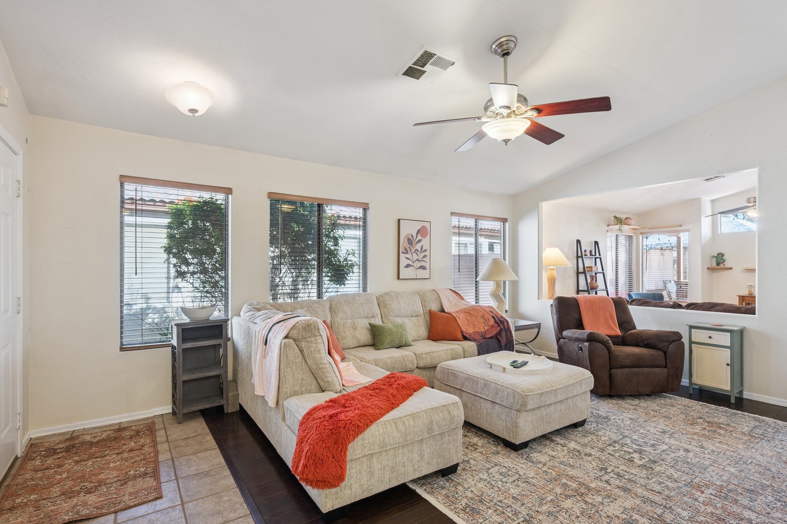Sink into the plush sectional sofa and feel the gentle breeze from your ceiling fan as natural light fills this welcoming living space.