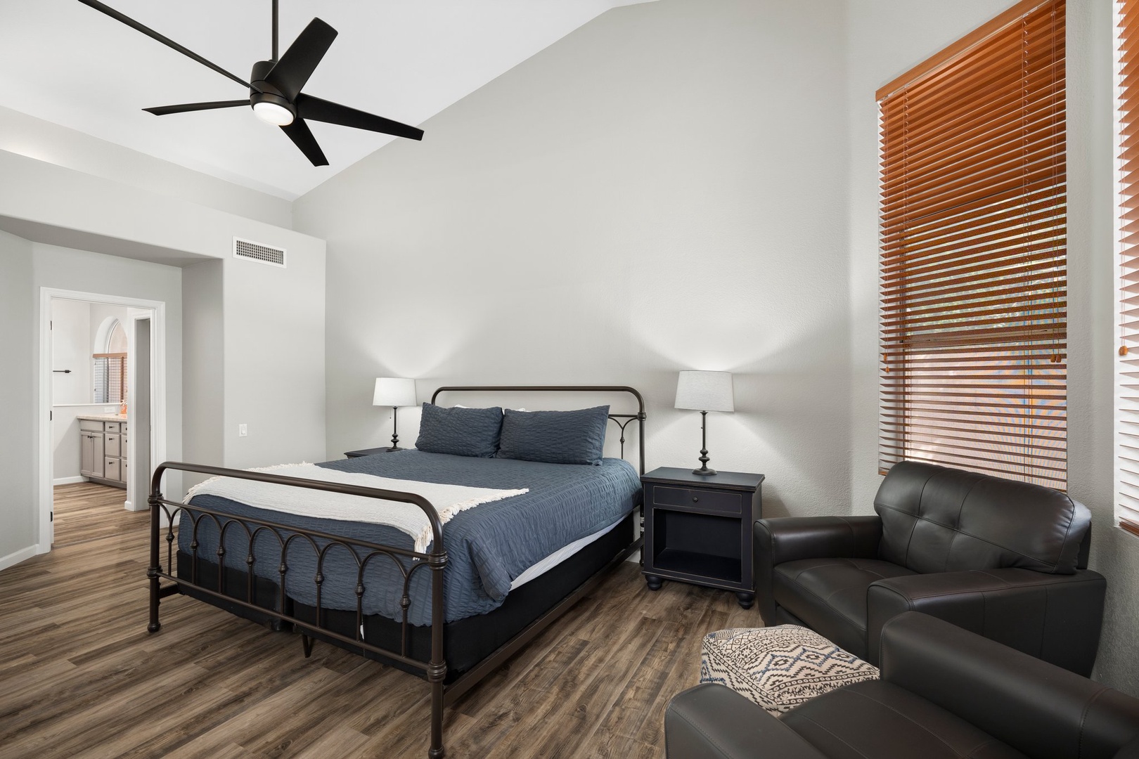 Primary Suite — King bed, ceiling fan, ensuite bath with dual-sink vanity, soaking tub, walk-in shower, and walk-in closet.