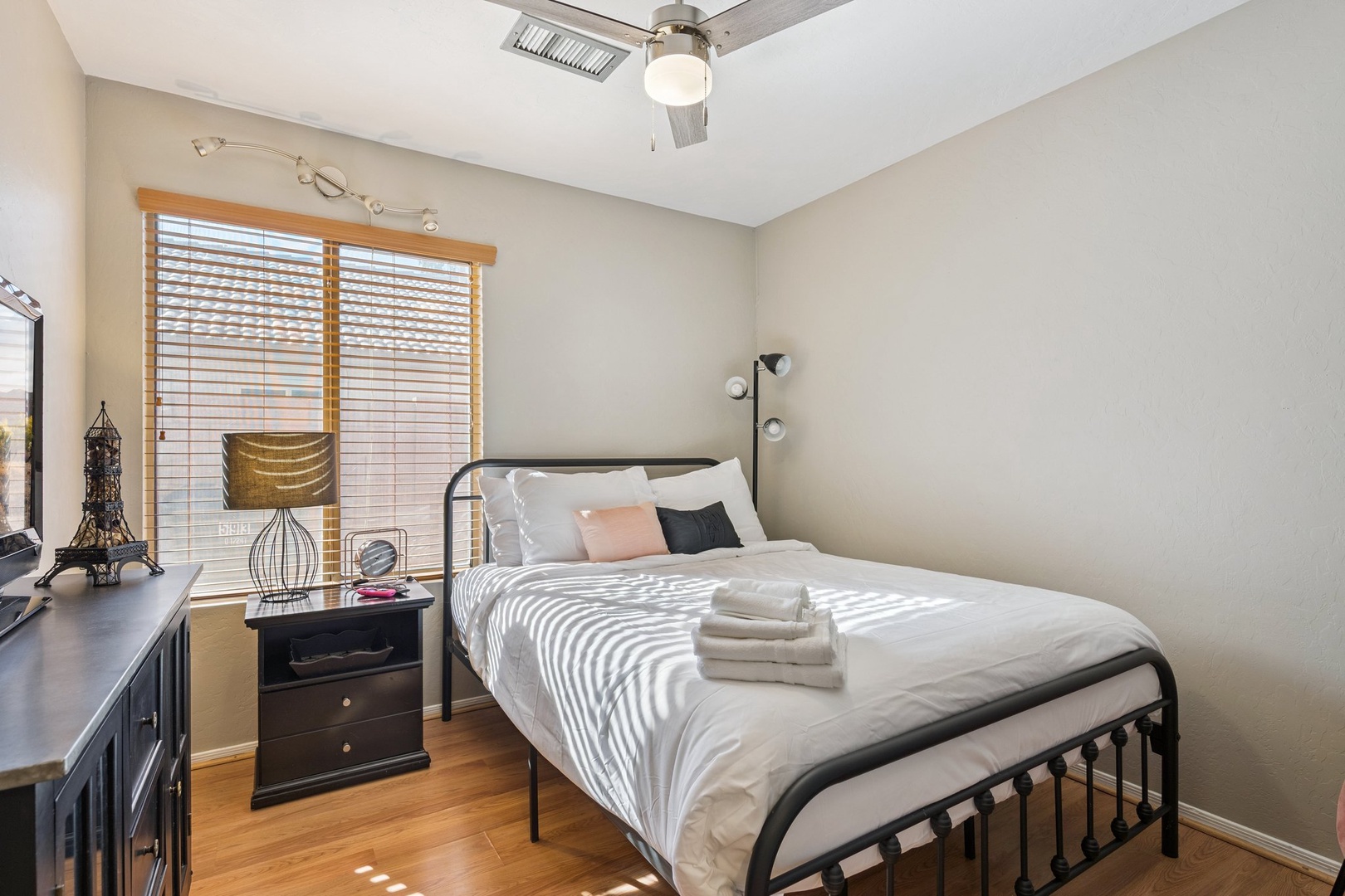 Unwind in your peaceful bedroom where soft natural light filters through wooden blinds, creating gentle patterns across crisp linens.