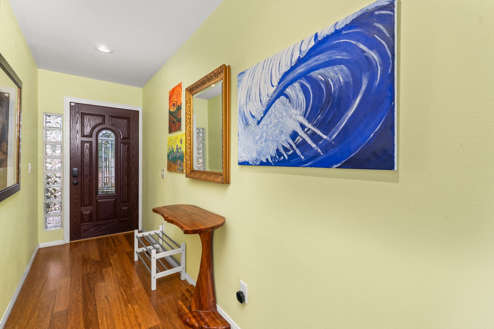 Step into your welcoming entryway where vibrant artwork and warm hardwood floors create an inviting first impression of your coastal retreat.