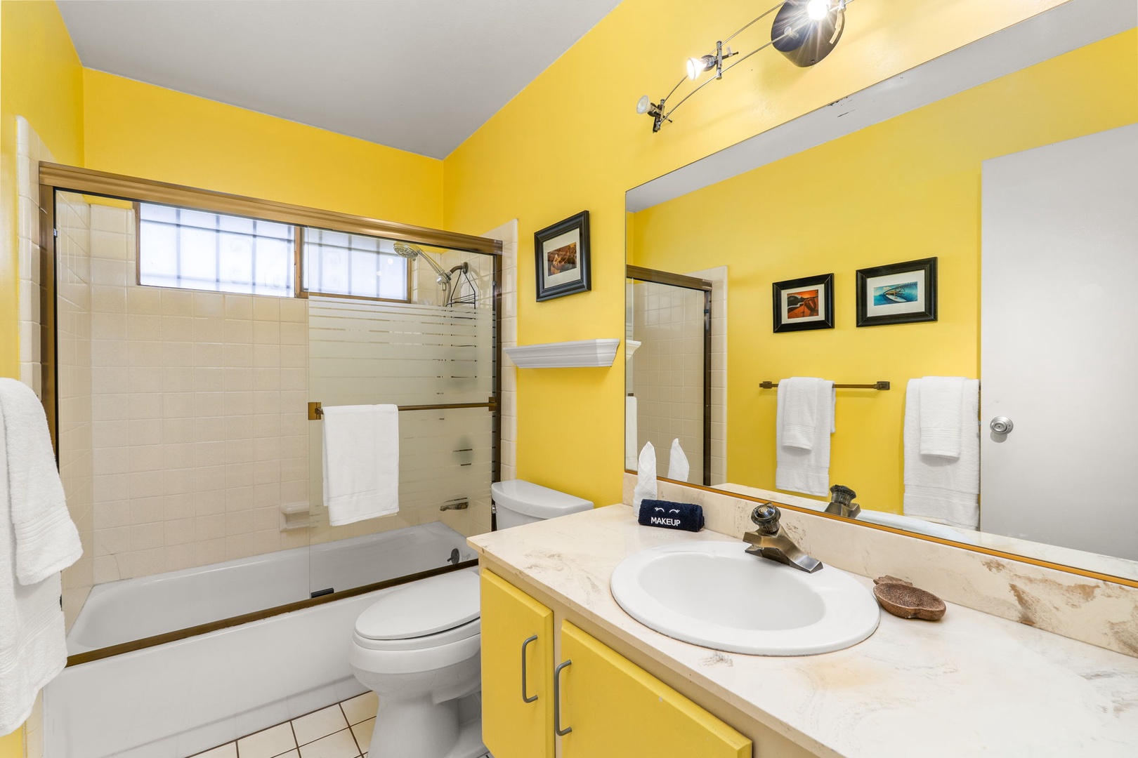 Brighten your morning in this cheerful yellow bathroom, complete with a spacious tub-shower combo and all the essentials for a refreshing start.