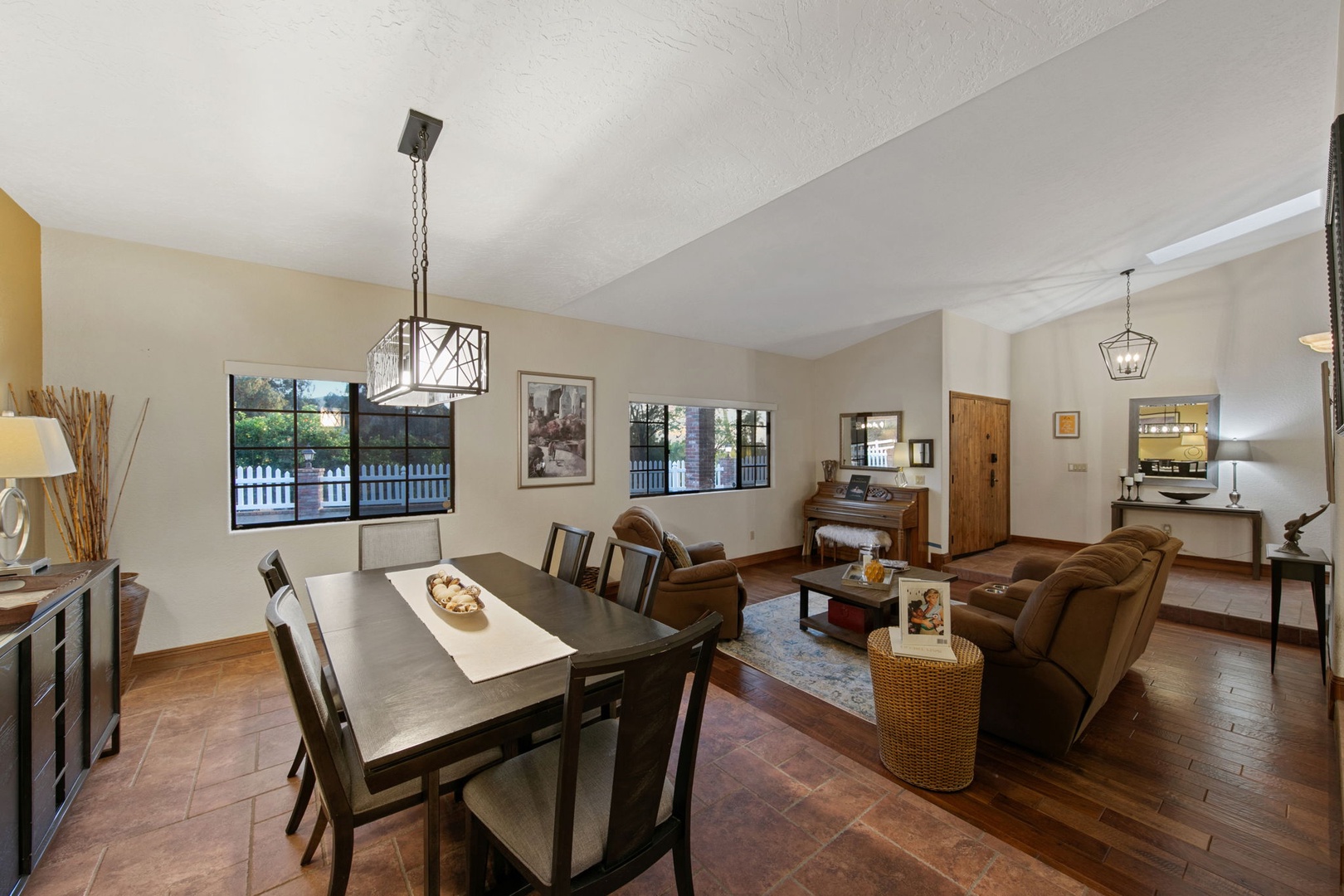 Your open-concept living space combines dining and relaxation seamlessly, with warm leather seating and natural light streaming through large windows.