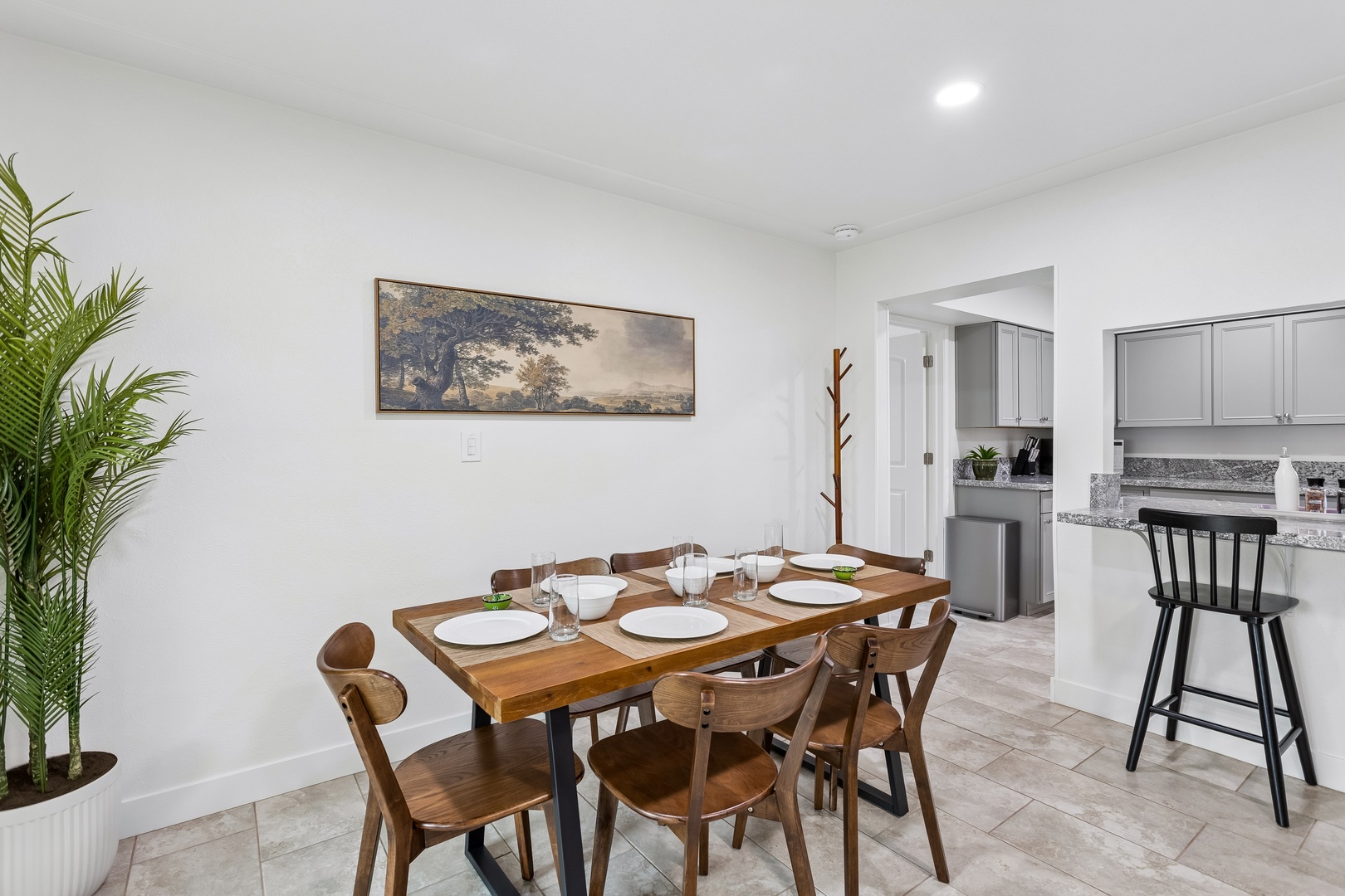 Gather around this welcoming dining table, perfectly set for your group to share stories and meals together in your bright, open space.
