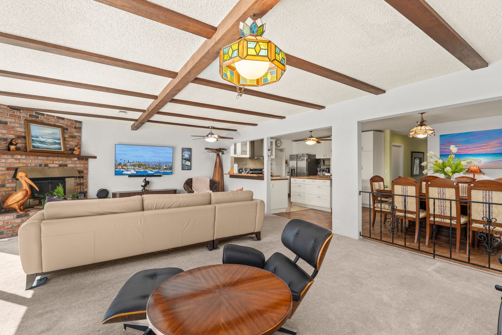 Relax in this spacious open-concept living area featuring exposed wooden beams, a cozy fireplace, and seamless flow to your kitchen.