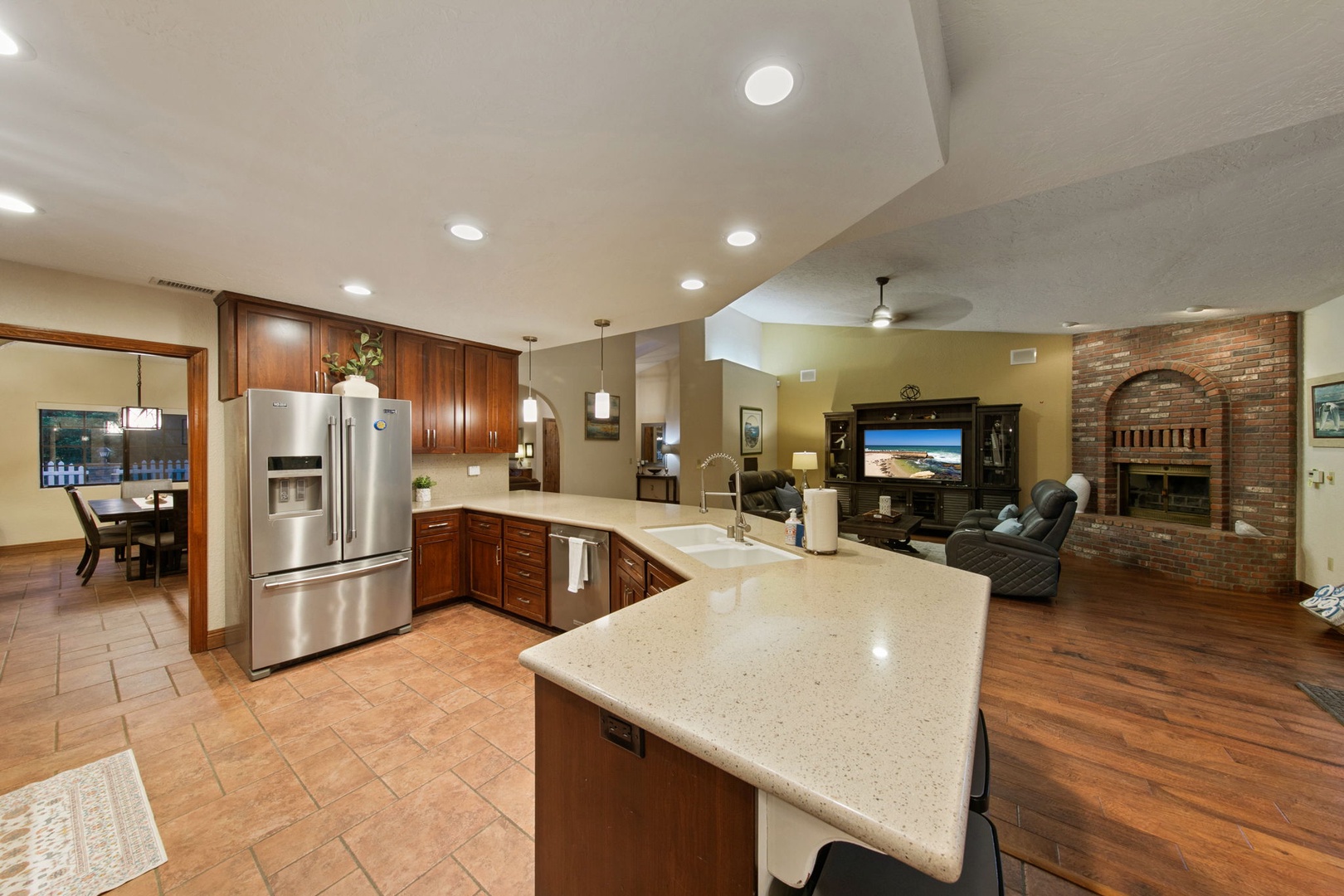 Gather in your spacious open kitchen with gleaming granite counters and stainless appliances, flowing into a cozy living area with warm brick fireplace.