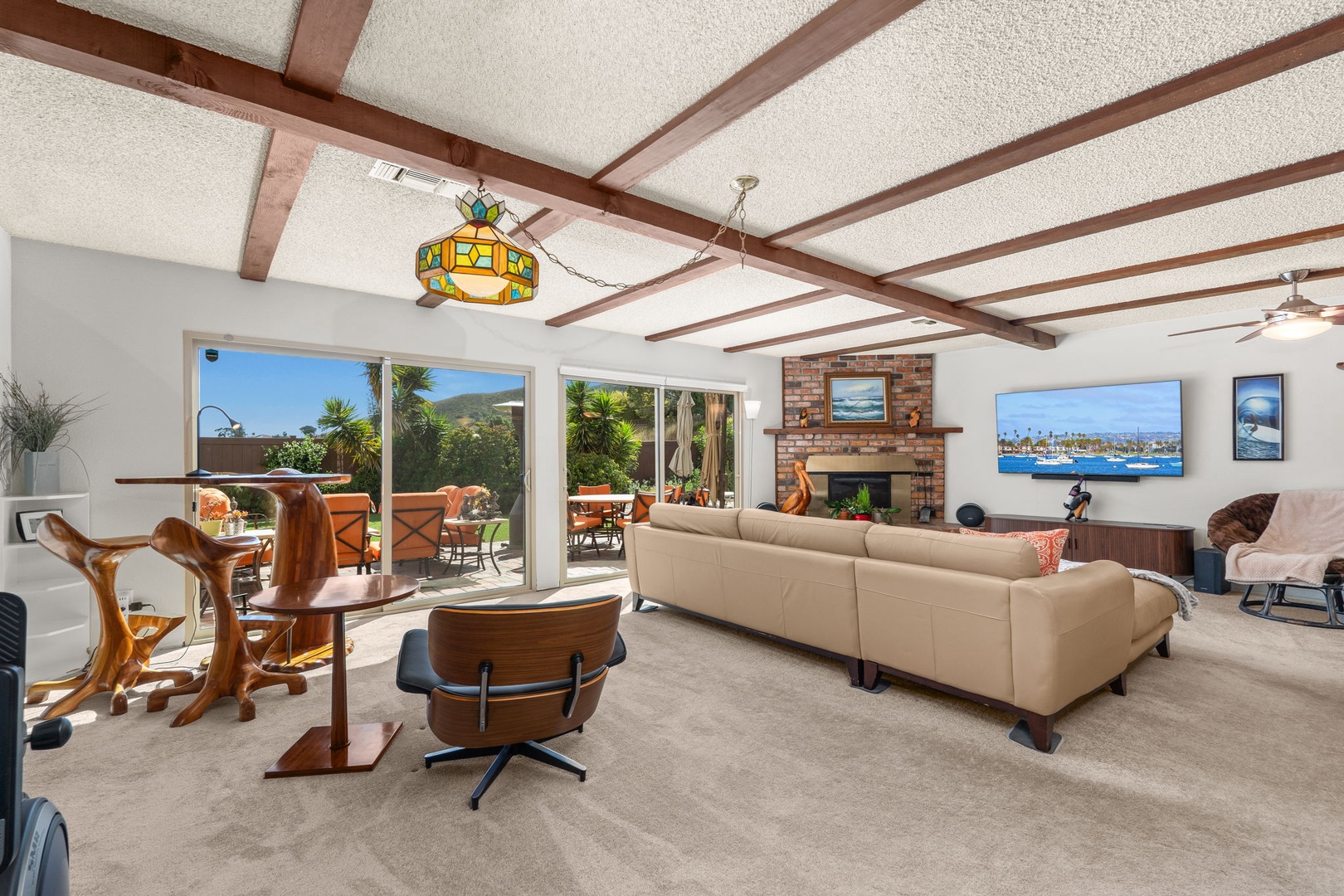 Relax in your spacious living room where warm wood beams frame bright windows revealing tropical views and your private patio beckons just beyond.