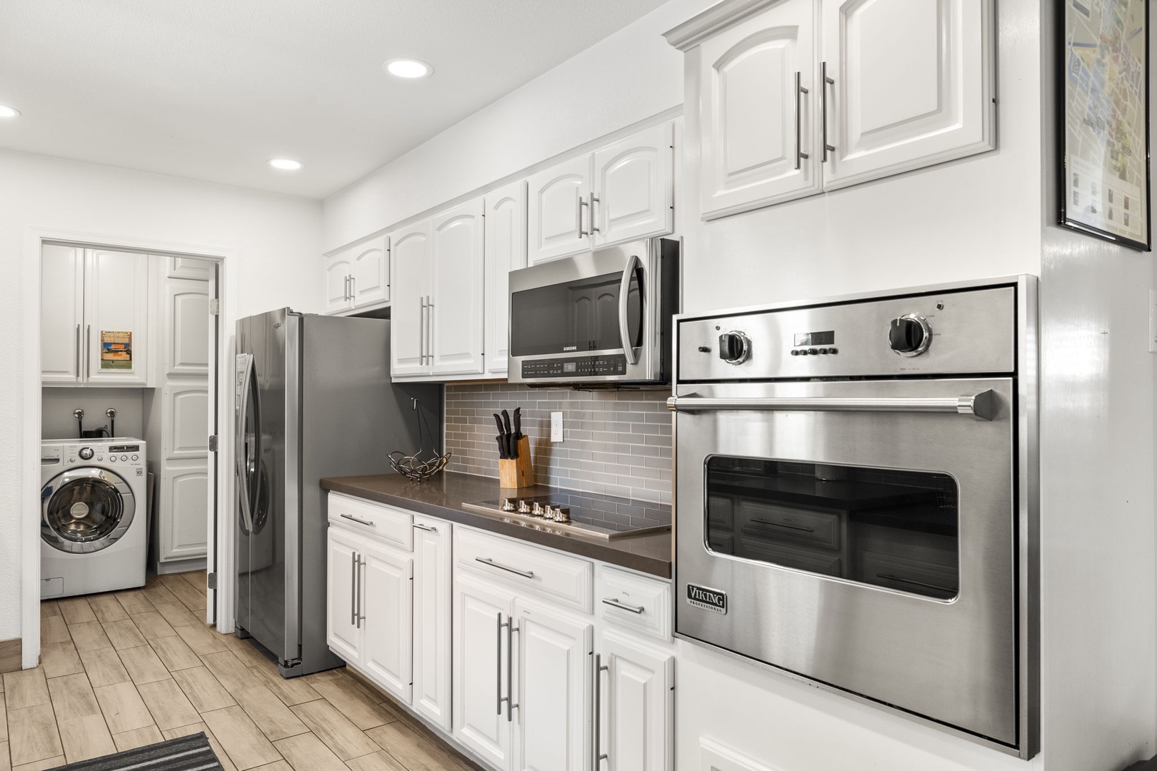 Kitchen has modern stainless steel appliances including: dishwasher, fridge, stove top, coffee maker, pots and pans, and utensils.