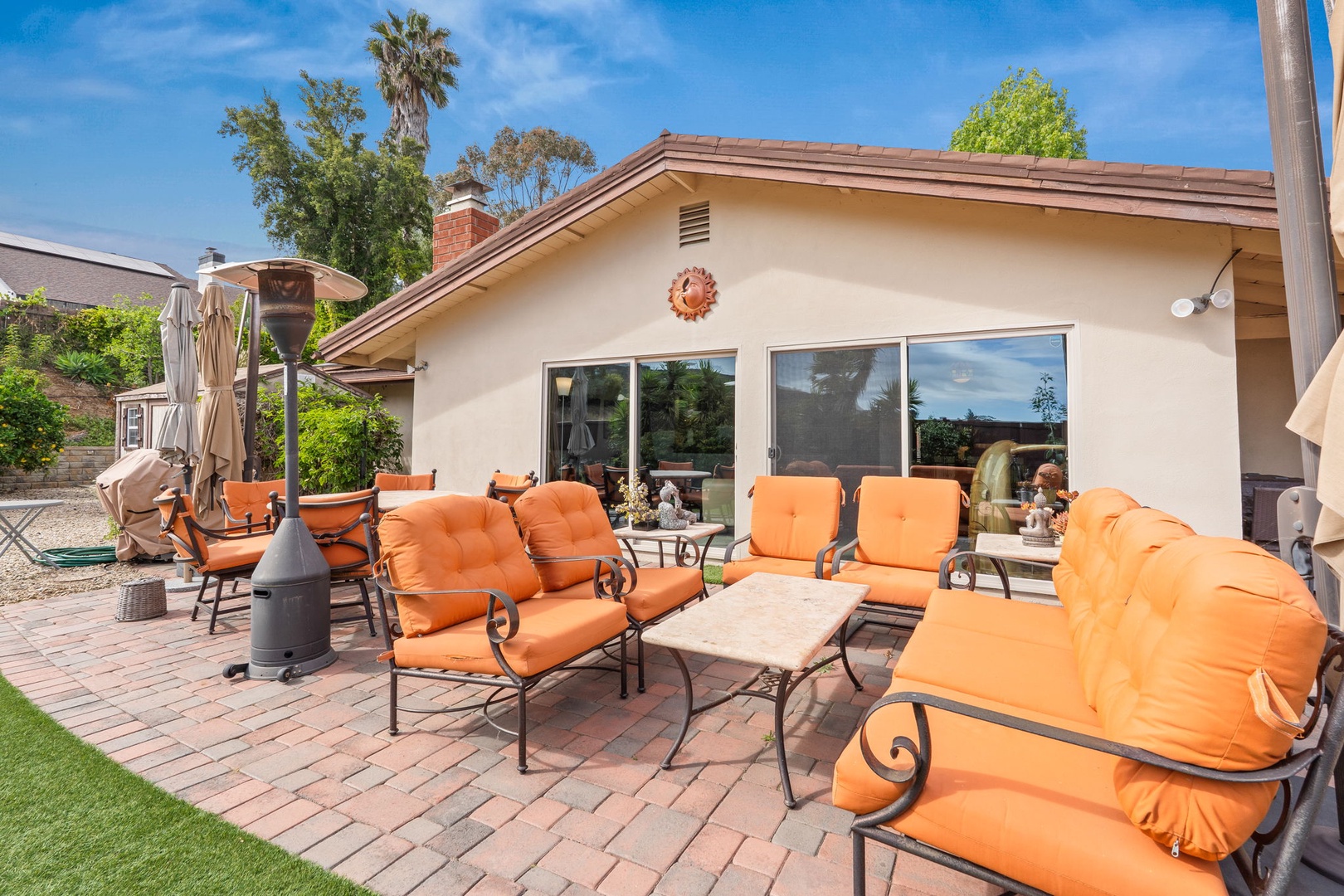 Relax on vibrant orange cushioned patio furniture while enjoying the spacious brick paver courtyard and peaceful residential setting.