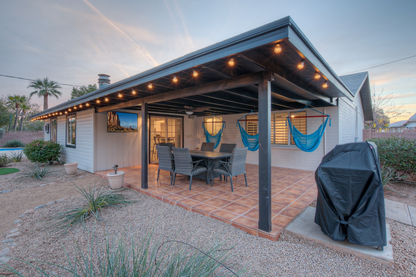 Outdoor lounge with hanging hammock chairs, fire pit table, and Flat Screen TV