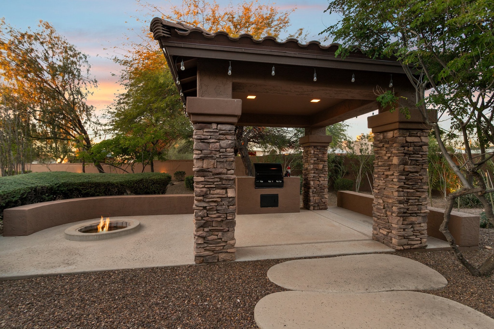 Gather around the fire pit for evening conversations under this elegant stone pavilion with built-in BBQ area.