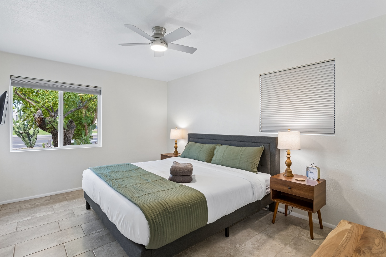 Sink into crisp linens and let the ceiling fan lull you to sleep. In the morning, gentle light streams through your window, offering a peaceful garden view to start your day refreshed.