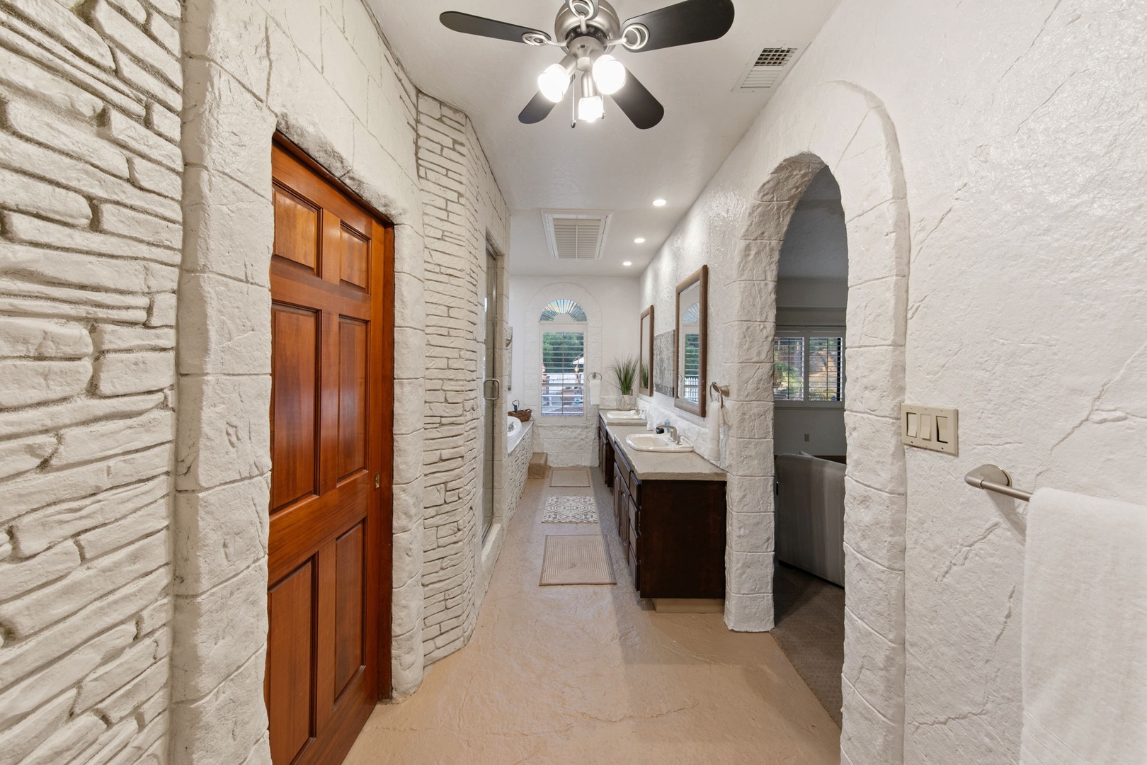 Step into your elegant ensuite primary bathroom sanctuary with exposed stone walls, vanities, and sophisticated archway design creating a spa-like retreat.