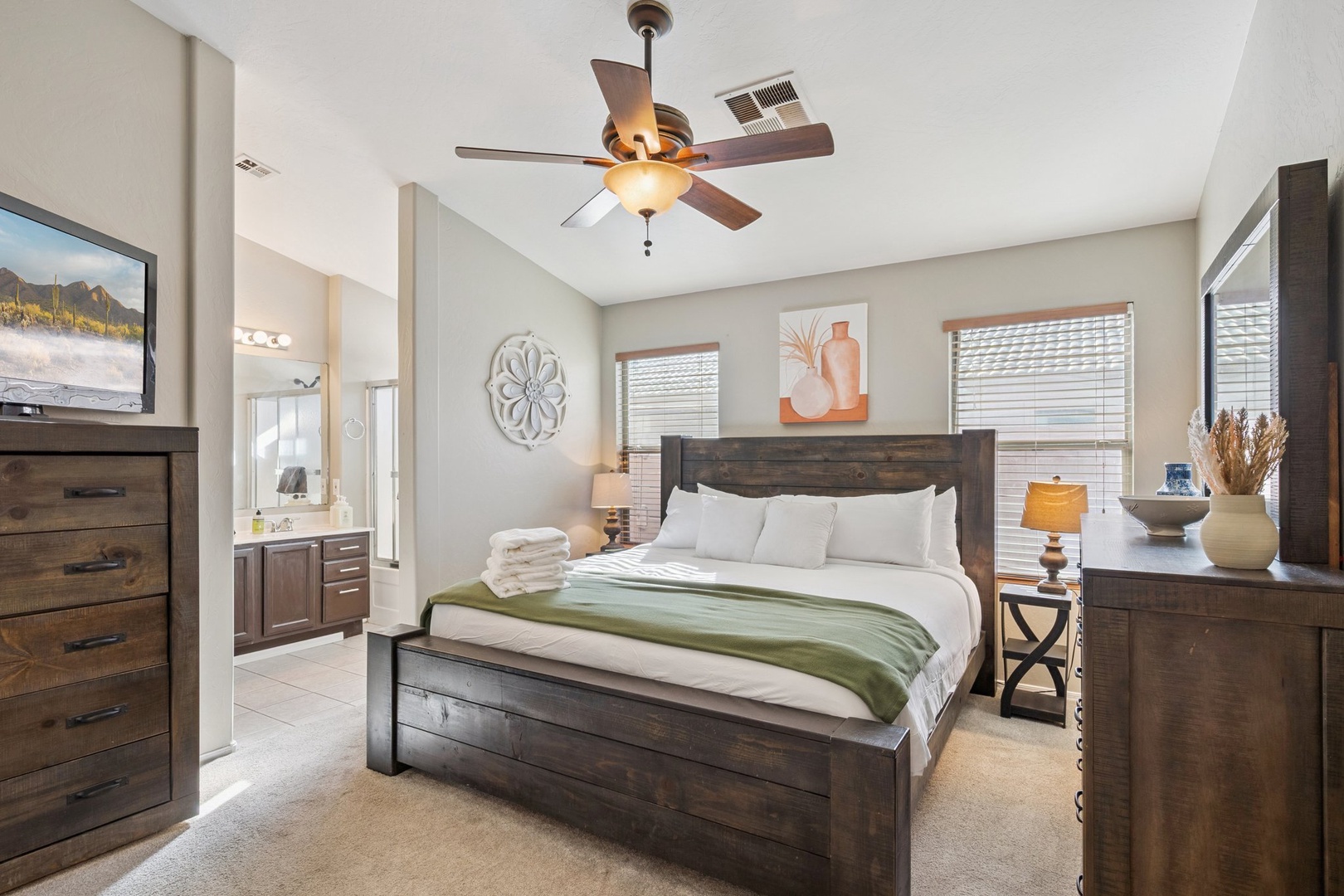 Sink into crisp linens and rustic charm with this bedroom's rich wood furniture, ceiling fan, and en-suite access for your perfect retreat.