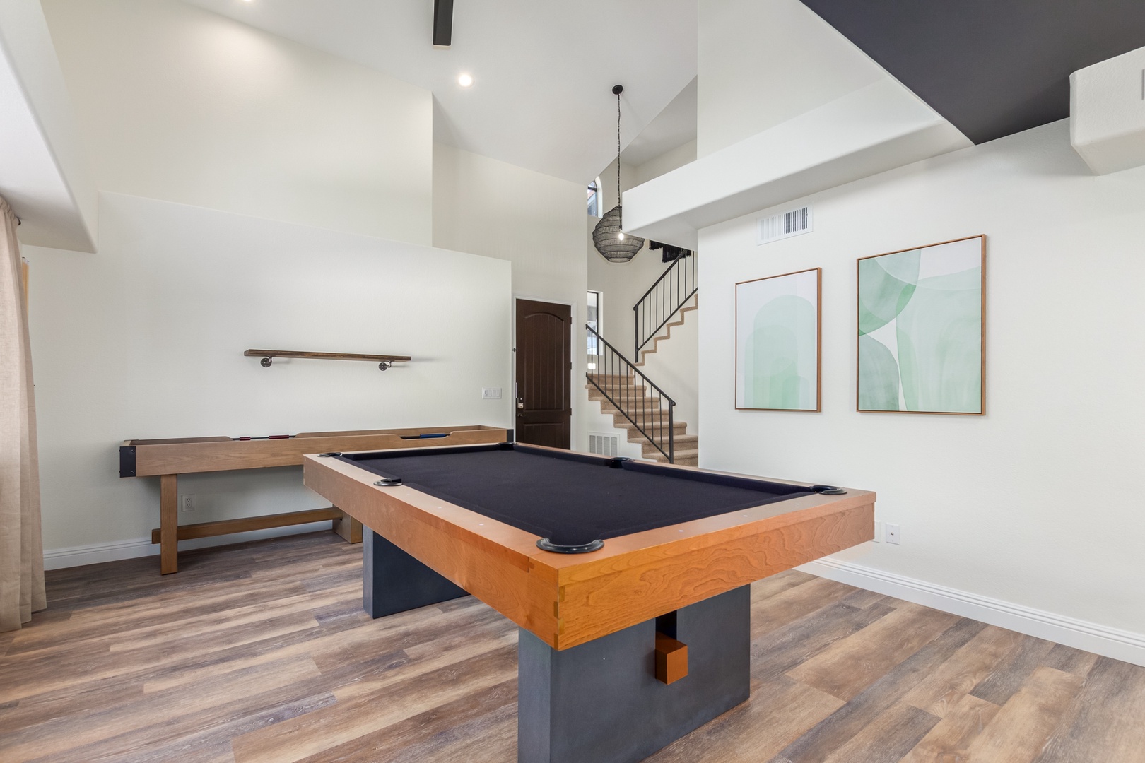 Adjacent to the kitchen and living room is a dining room table with seating for 8 people, pool table, and a shuffle board table.