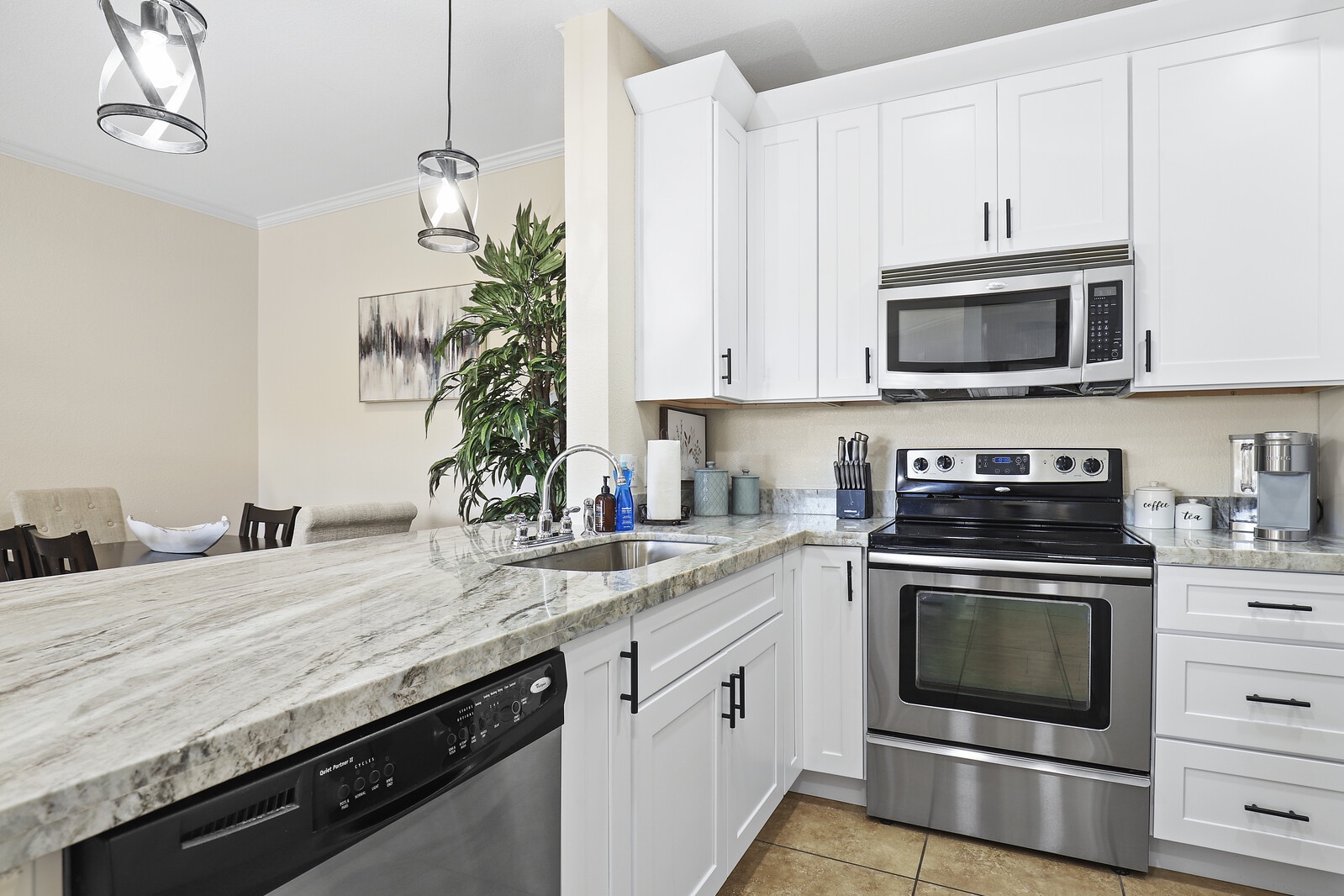 Kitchen offers modern stainless steel appliances including: dishwasher, fridge, stove top, coffee maker, pots and pans, plates, and utensils.