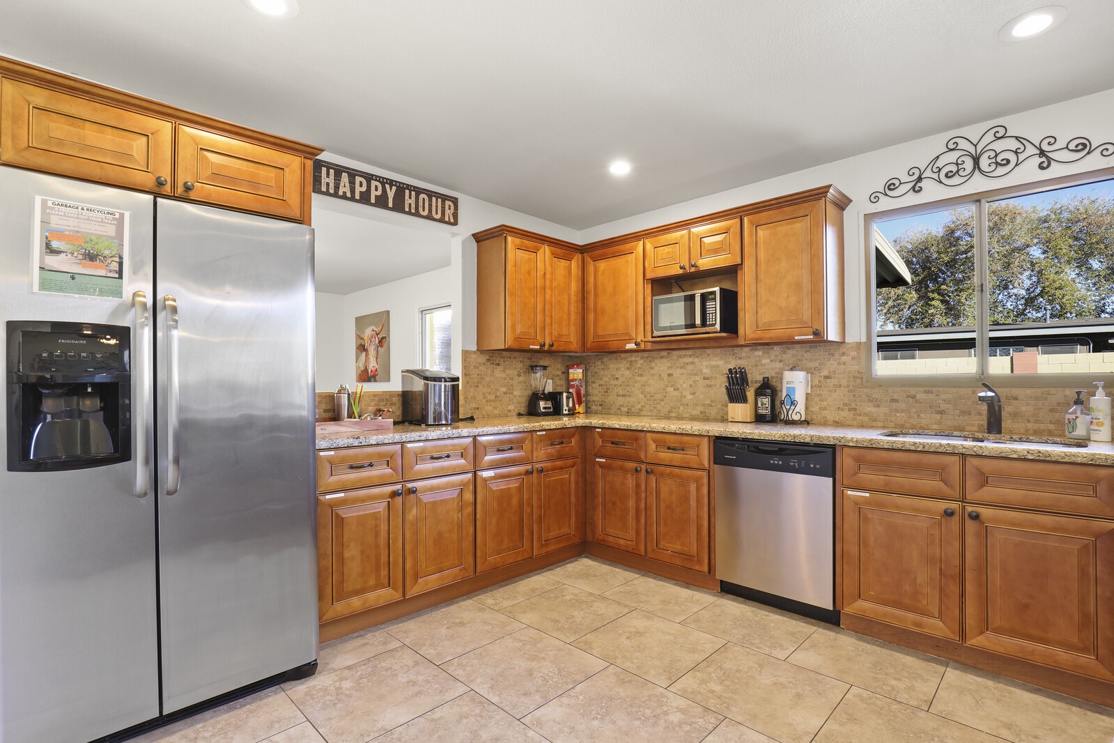 Modern stainless steel appliances including: dishwasher, fridge, oven, microwave, stove top, coffee maker, pots and pans, and utensils.