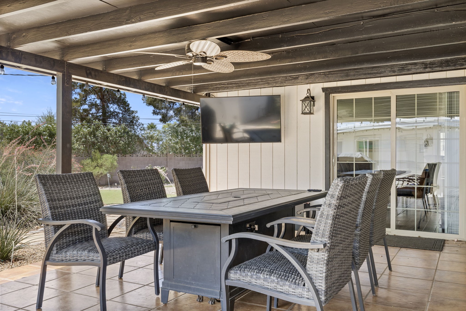 Outdoor lounge with hanging hammock chairs, fire pit table, and Flat Screen TV