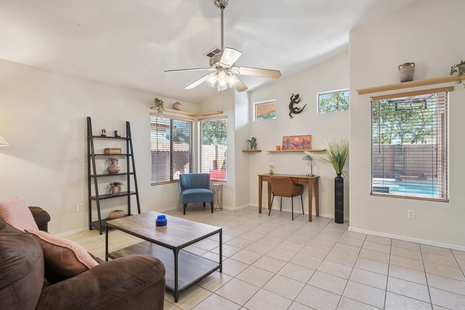 Relax in your bright living space with comfy seating, work desk, and peaceful pool views through large windows.