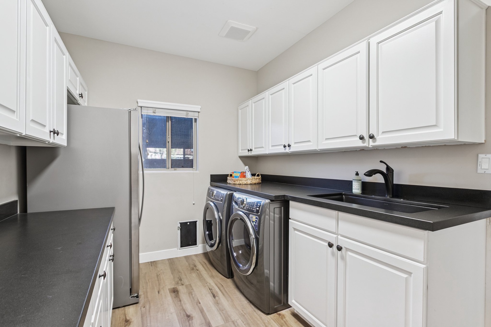 Your bright laundry room features sleek black countertops and white cabinetry, making household tasks feel effortless during your stay.