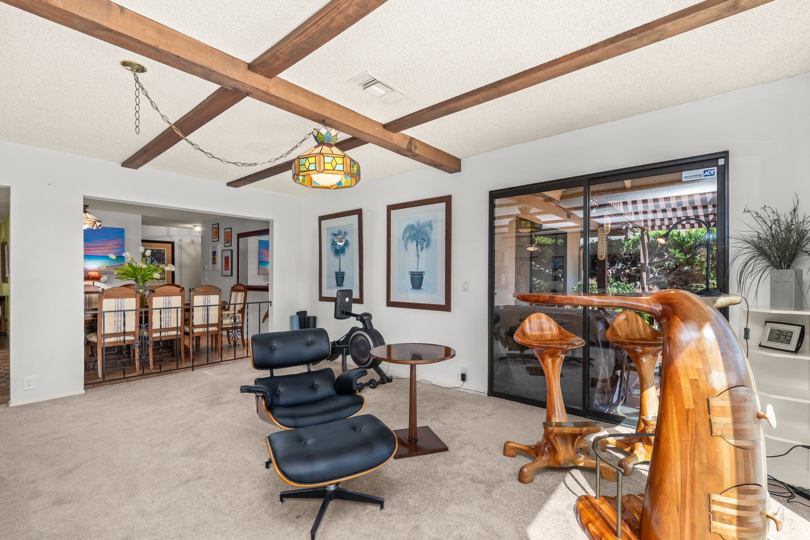 Relax in this stunning living space with exposed wooden beams, elegant furnishings, and abundant natural light streaming through large windows.