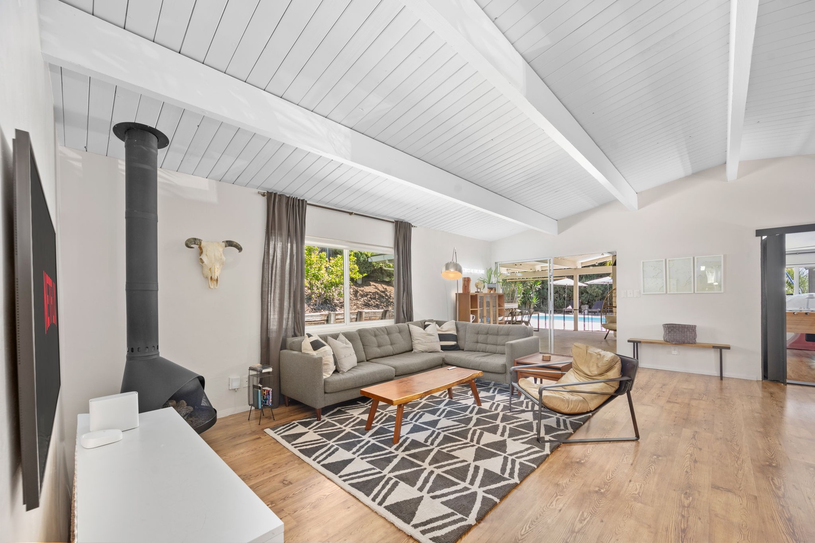 Unwind in your bright, airy living room with vaulted ceilings, cozy fireplace, and stylish mid-century decor. Natural light floods in, while glass doors open to your private pool oasis.